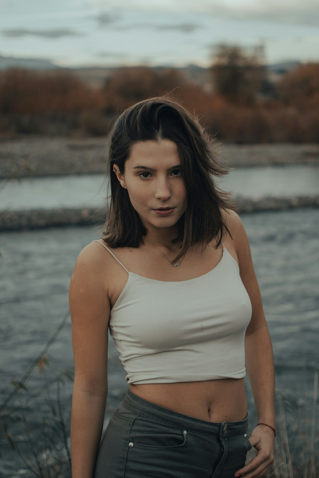 woman in white tank top standing near body of water during daytime